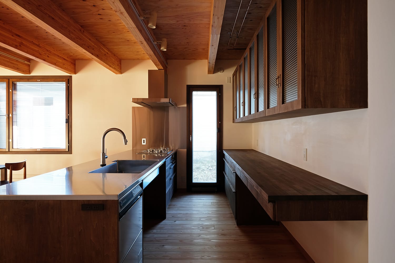 キッチン周りの造作家具を横から 食器棚ガラス扉と木製カウンターと引き出しとステンレスカウンターと扉と引戸