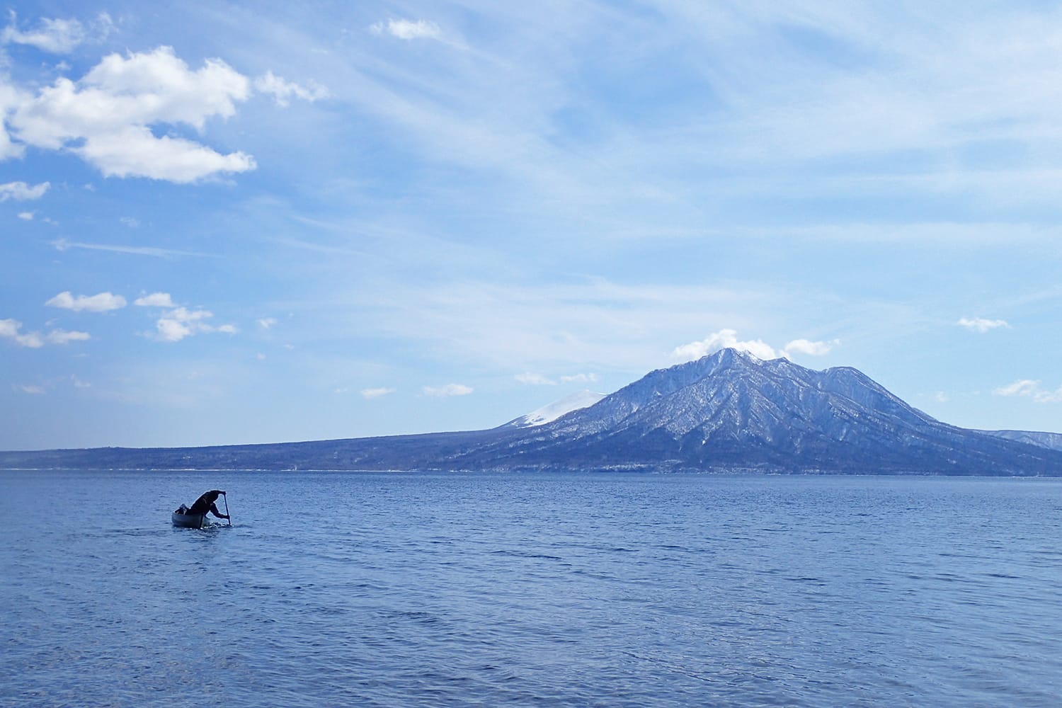 早春の支笏湖にて風不死岳に向かってカヌーを漕ぐ