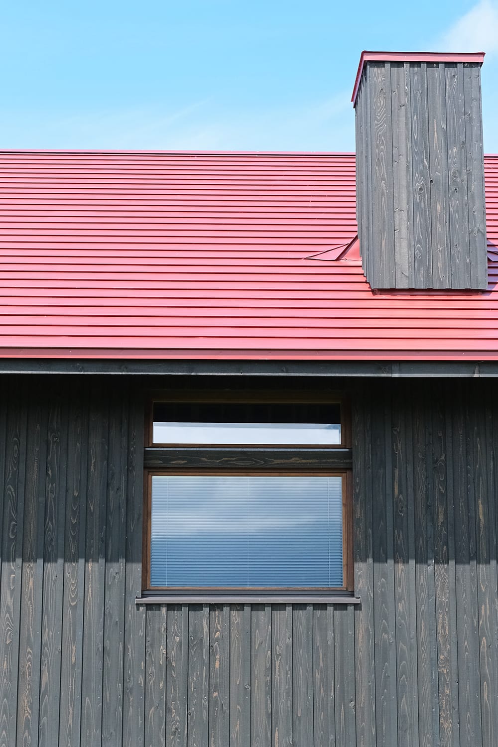 黒い板張りと赤い屋根と煙突のある家