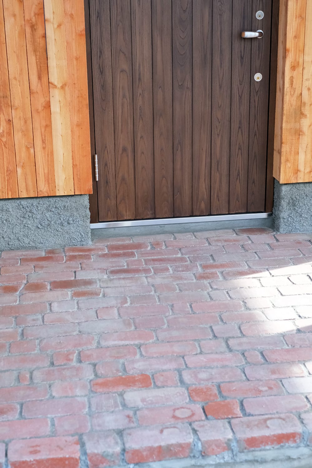 赤レンガ敷きと板張り玄関ドアの玄関ポーチ