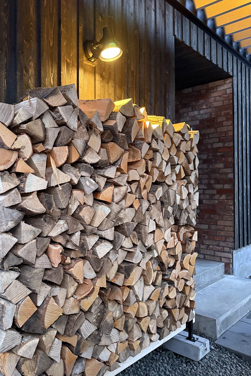 新築住宅の玄関脇に積まれた広葉樹の薪