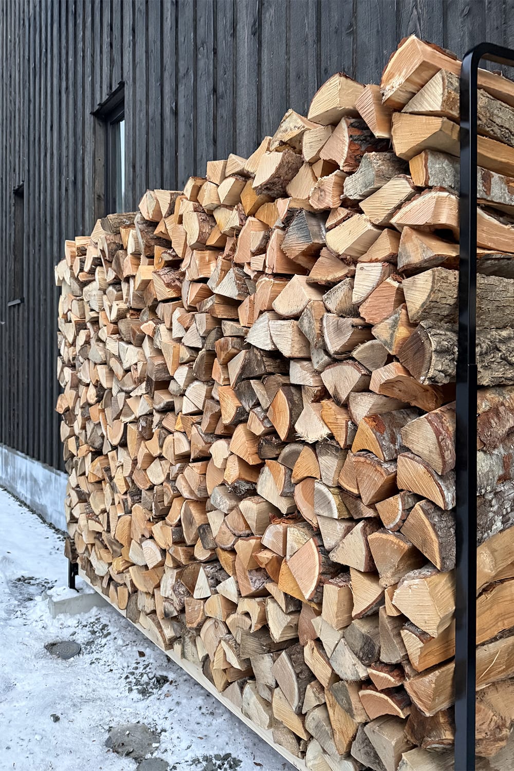 新築住宅の外壁横に積まれた広葉樹の薪