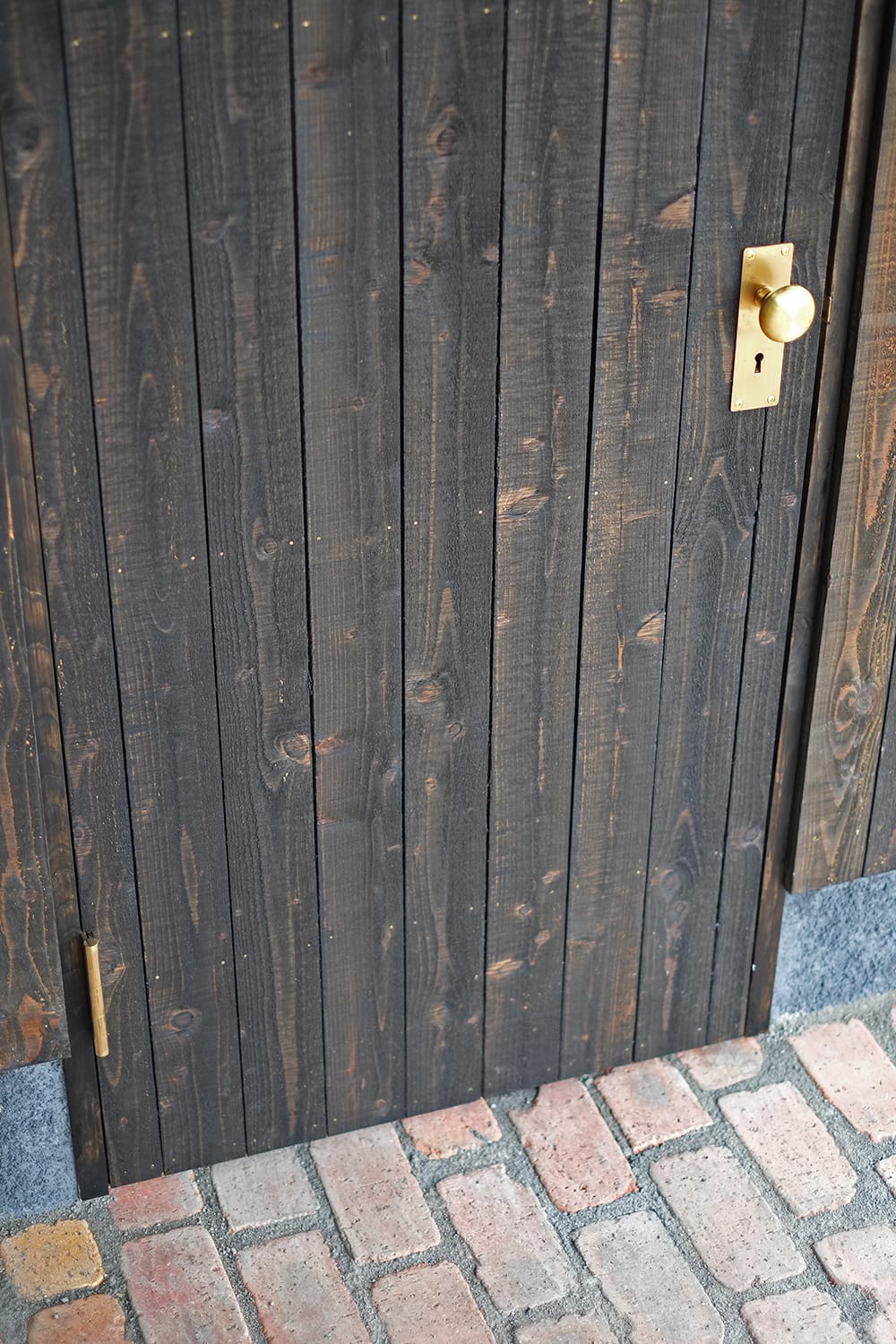 レンガ敷きの土間とカラマツ縦板張りのドアと真鍮製のドアノブ