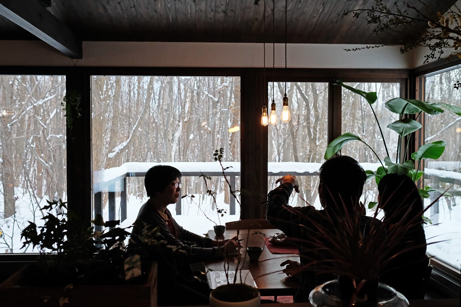 雪が積もる雑木林を眺めながらダイニングテーブルにて