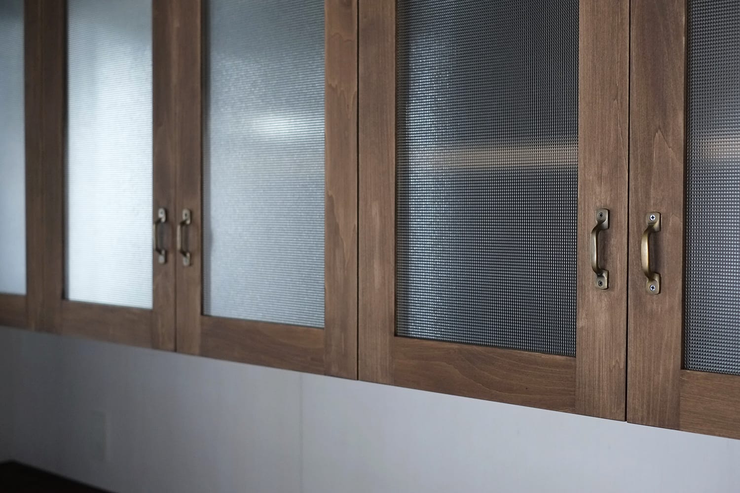 細かい格子柄（ドットパターン）のレトロガラスがはめ込まれ真鍮ハンドルが付いた食器棚の扉