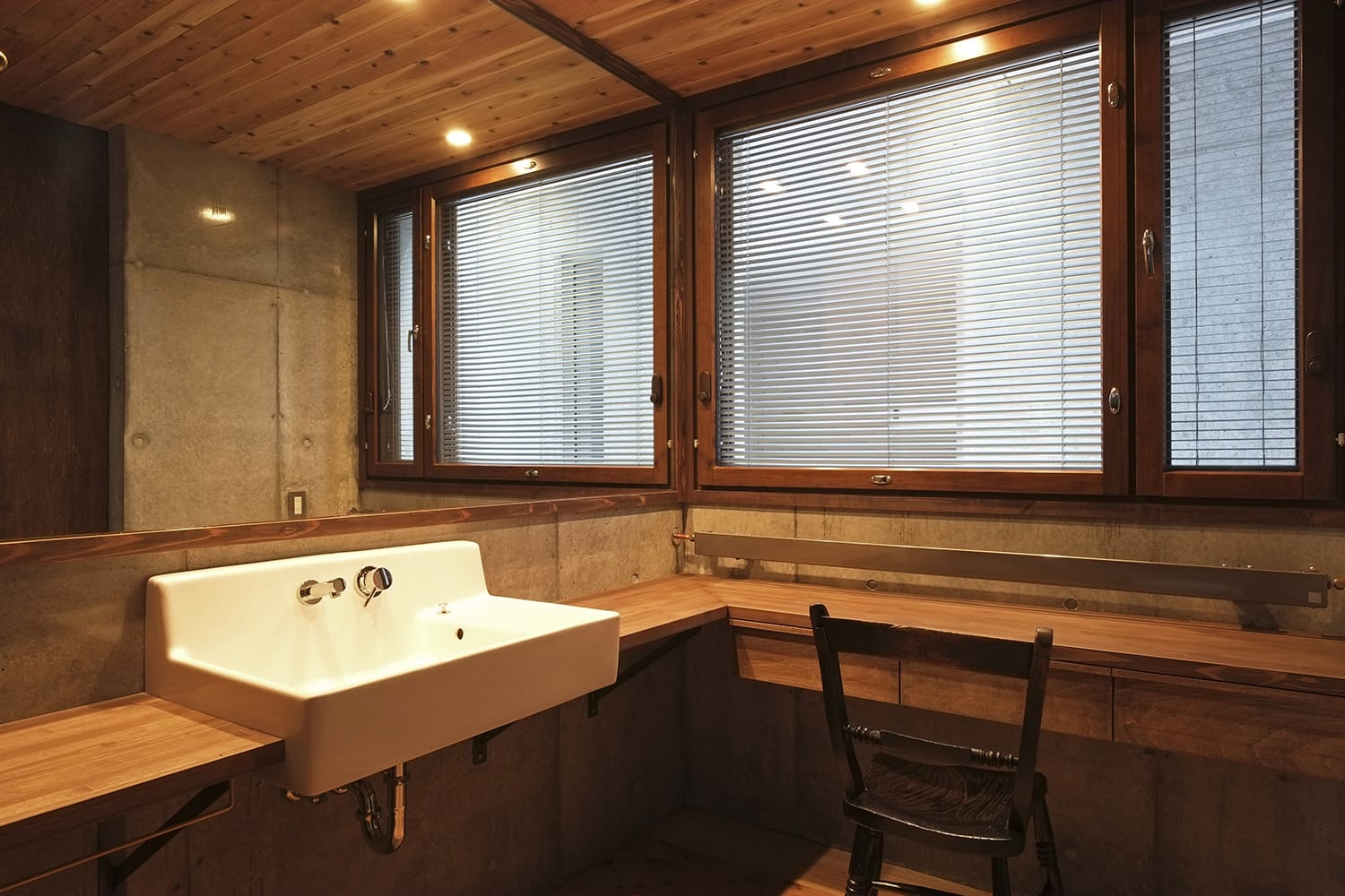 コンクリート打放し壁と木製カウンターのパウダールーム（洗面化粧室）