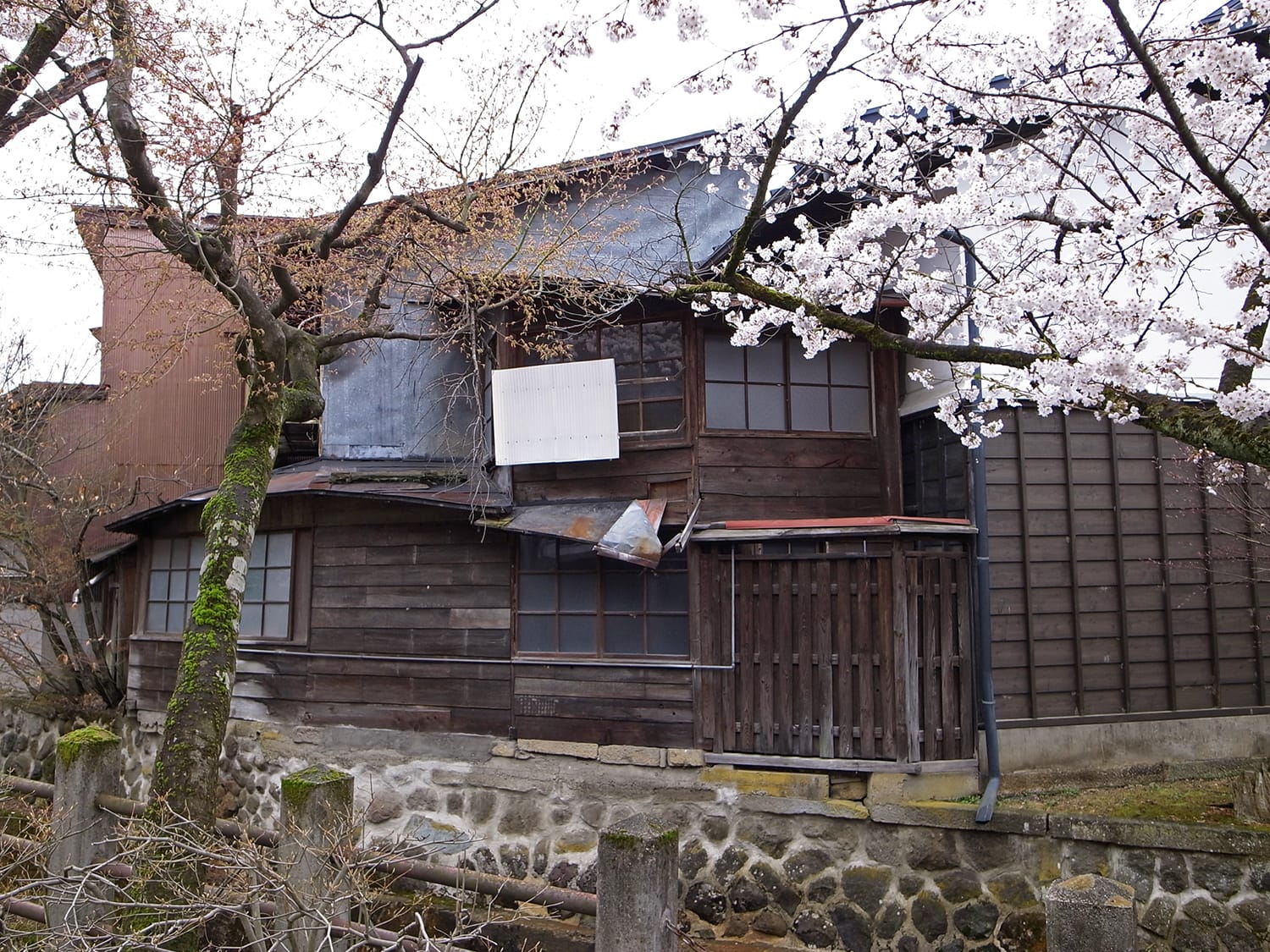 再生工事（改修工事）前の古い町家（古民家）を江名子川越しに見る外観2