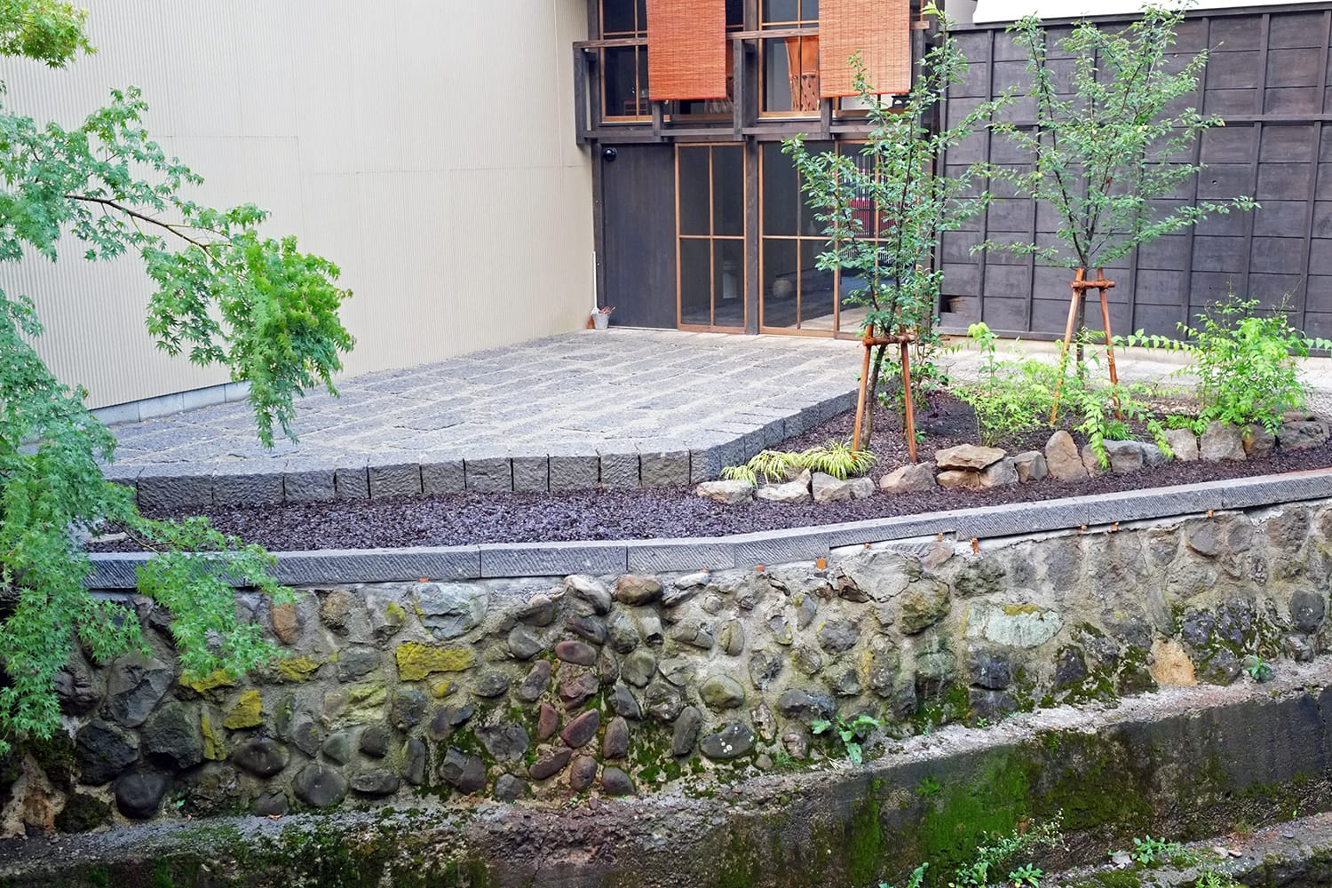 再生された町家とそのうらの石畳の石庭と江名子川の石積み護岸