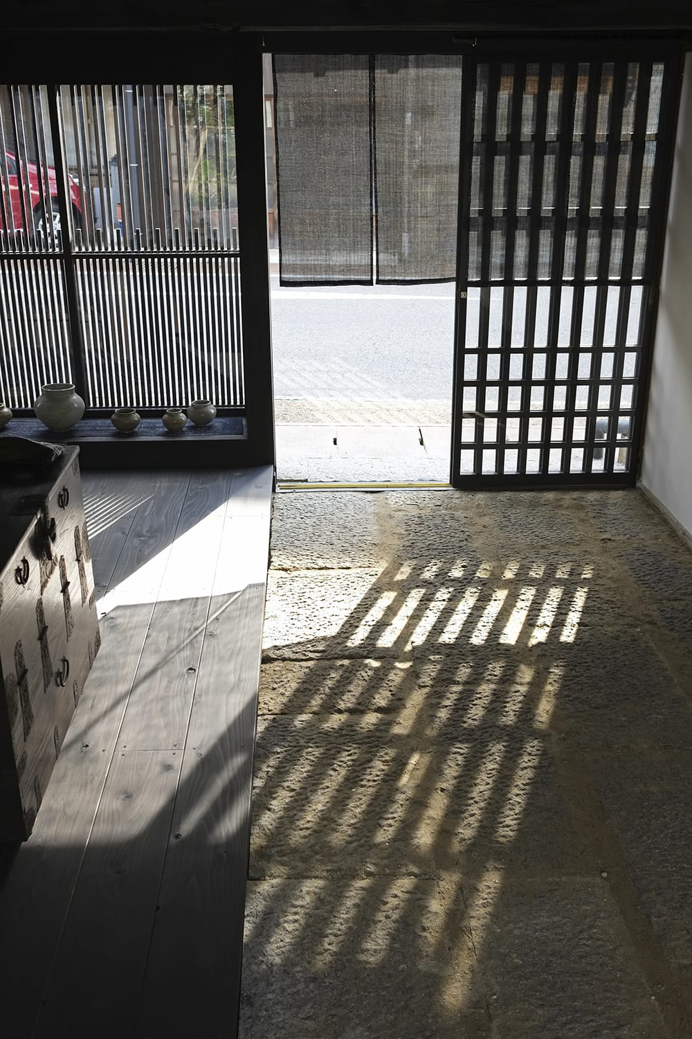 玄関引戸の格子の影が石敷きに映る