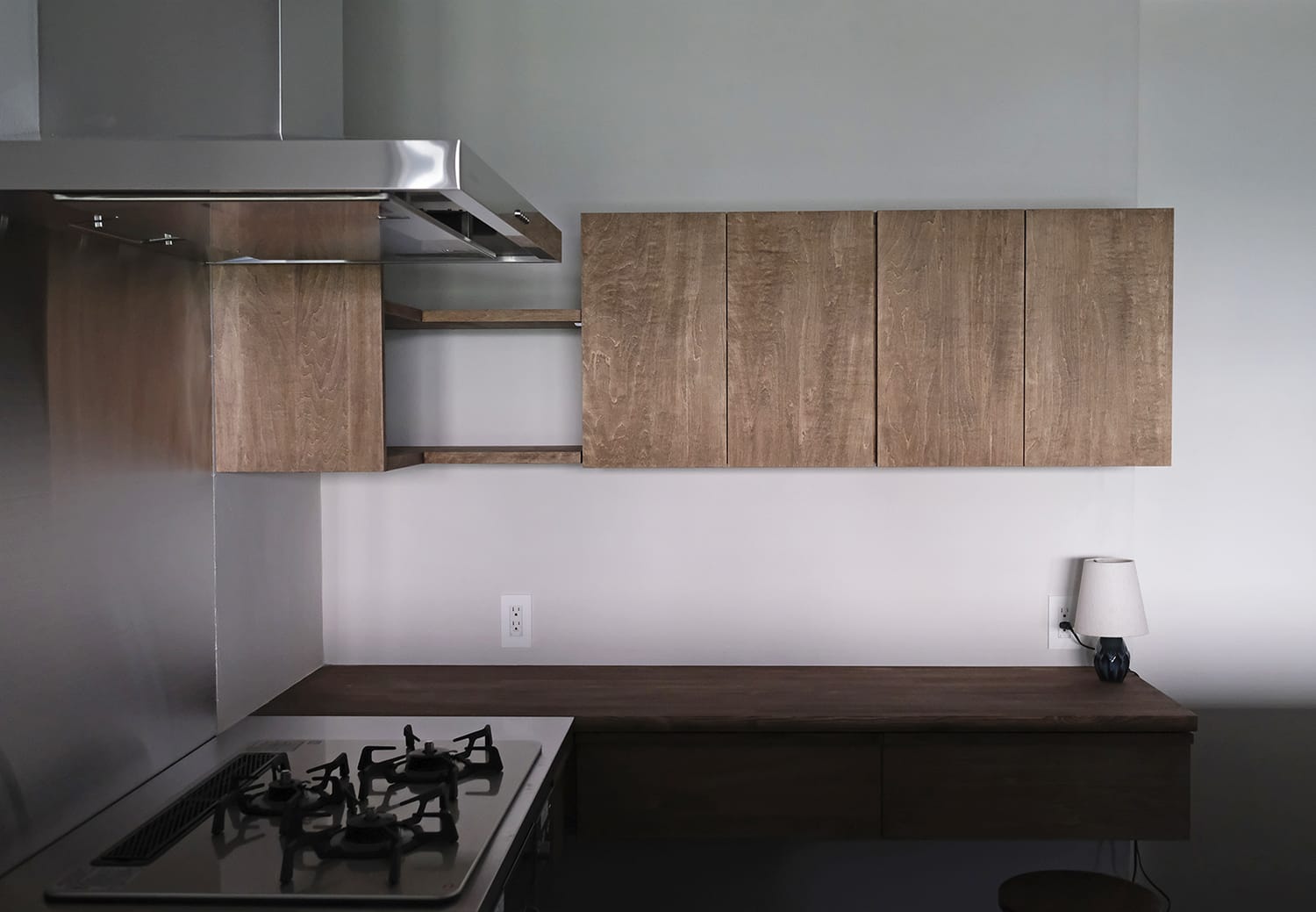 キッチンのこじんまりとシンプルな木製の作業カウンターと壁付け収納棚
