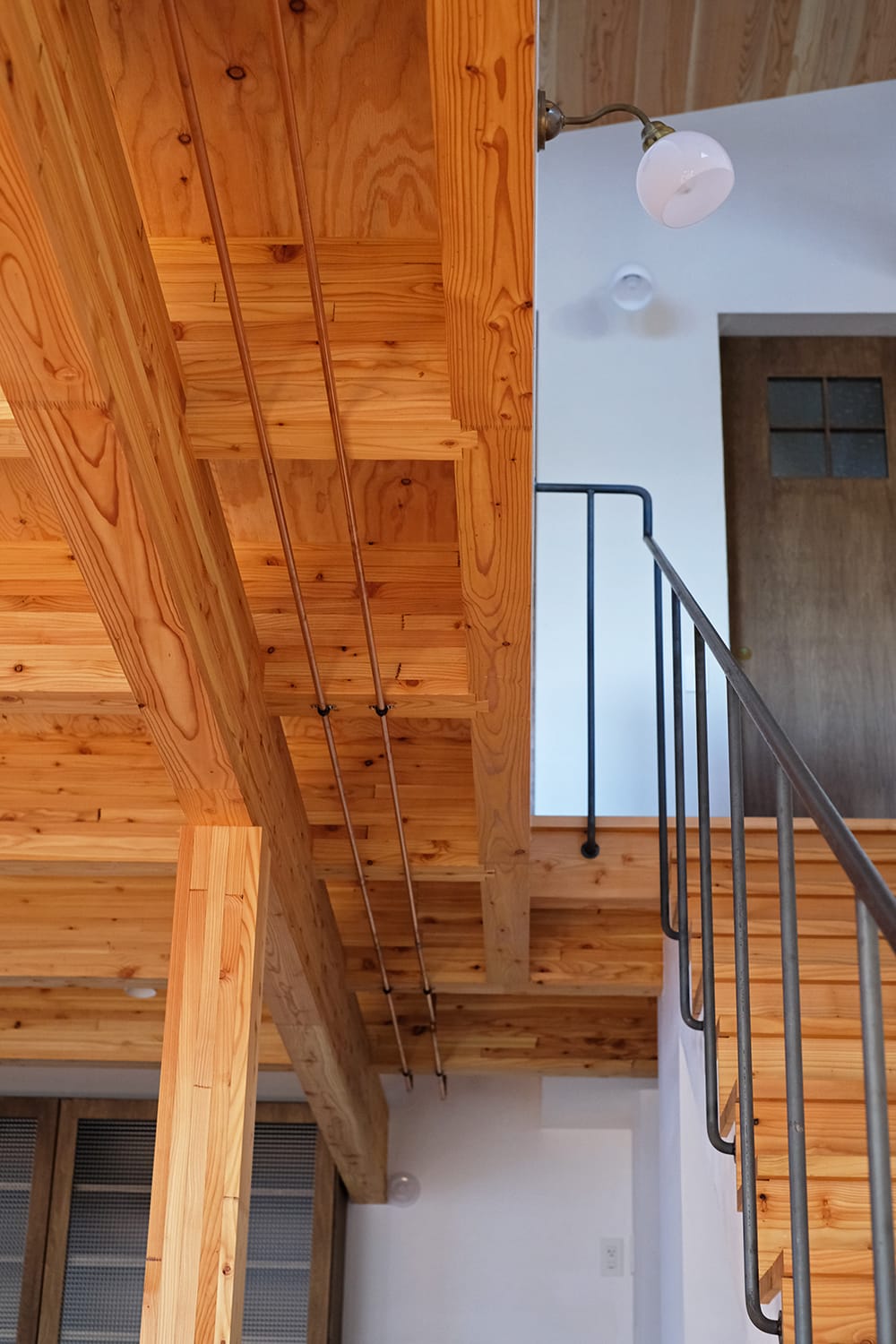 北海道産カラマツの2階床梁組みと暖房温水銅配管と鉄の階段手すり