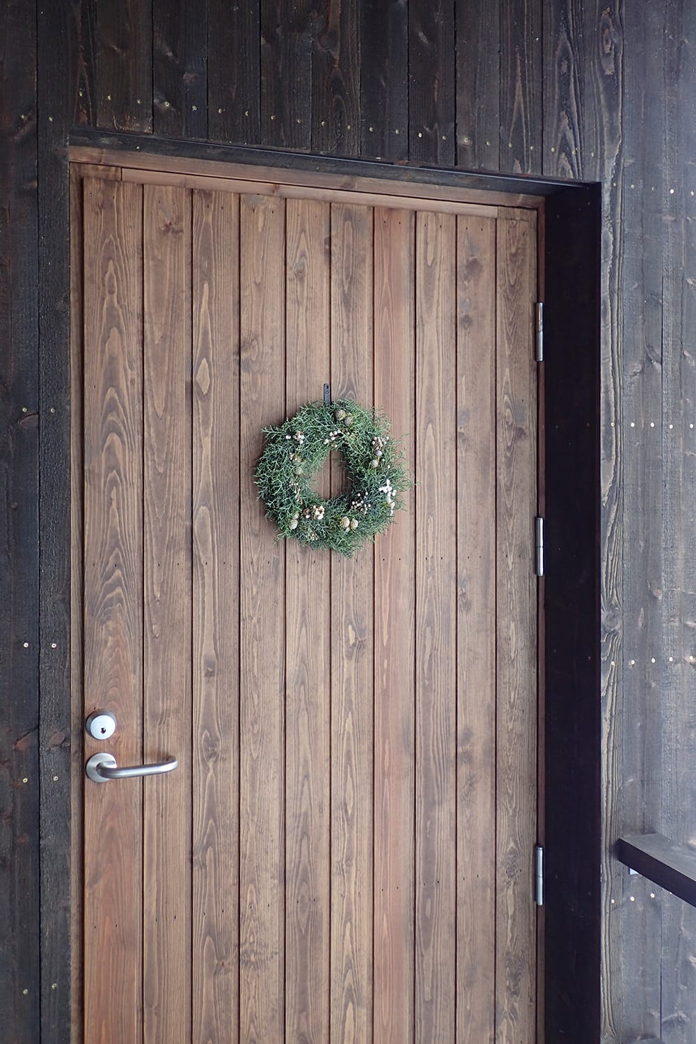 リースが掛けられたげ木製玄関ドア