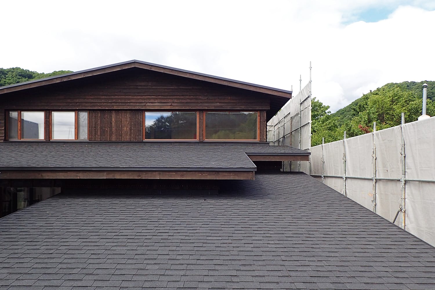 カラマツ板張りの外壁とアスファルトシングル葺きの屋根