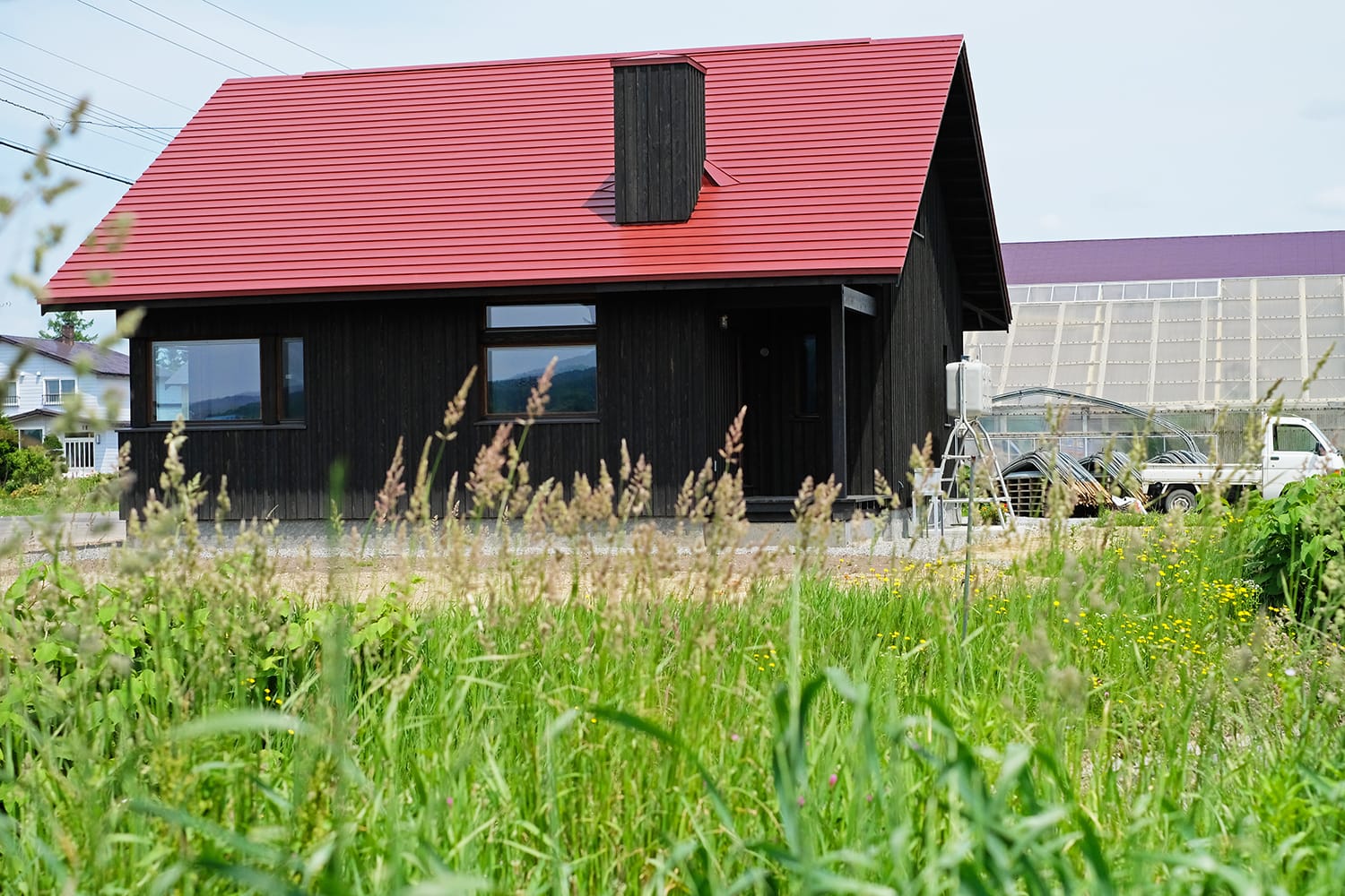 赤い板金屋根と黒い縦板張り外壁の家