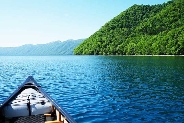 夏の新緑濃い支笏湖でカナディアンカヌーを漕ぐ