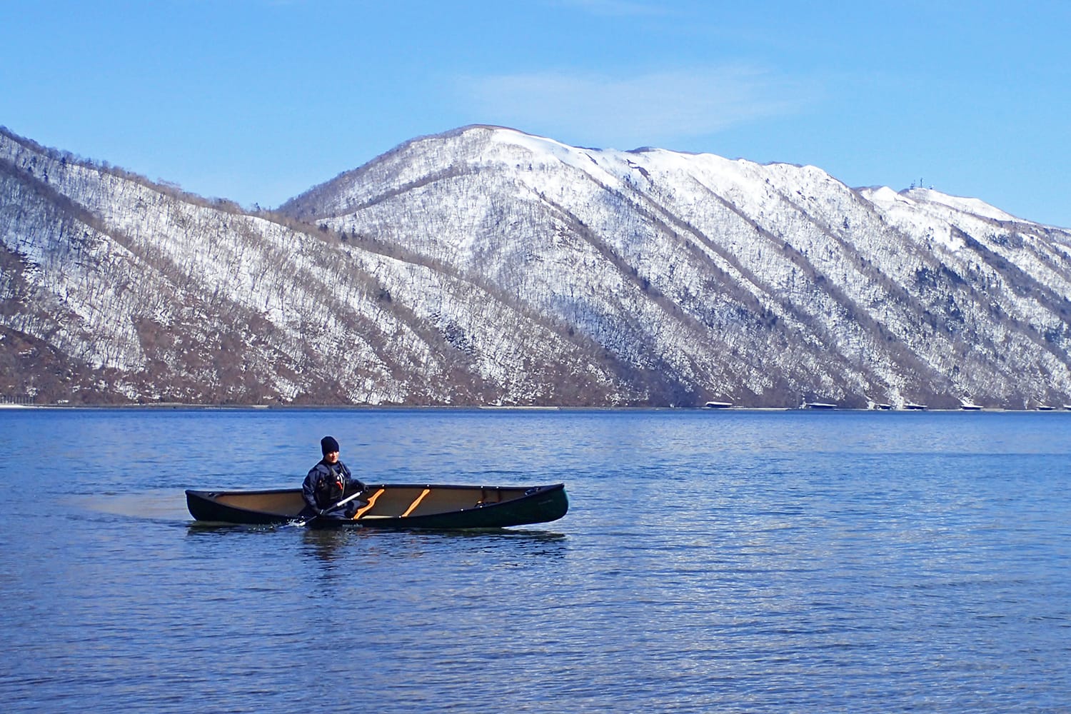 早春の残雪風景の支笏湖にてカナディアンカヌーを傾けて（リーン）走らせる
