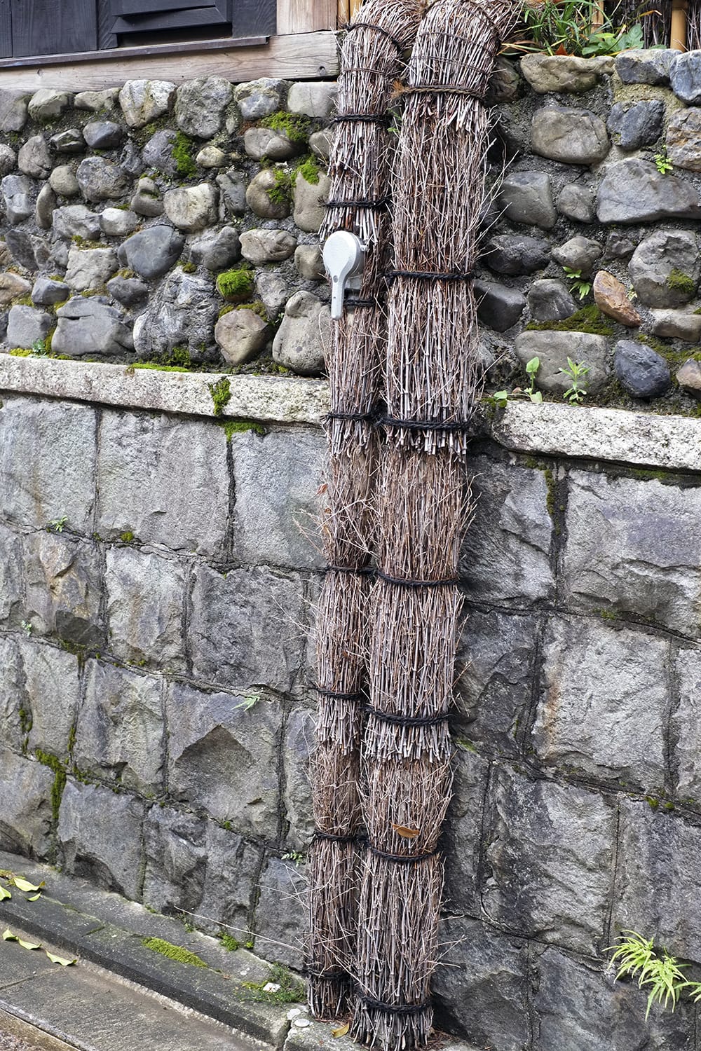 京都の石塀小路の水道管に竹の小枝が巻き付けられている