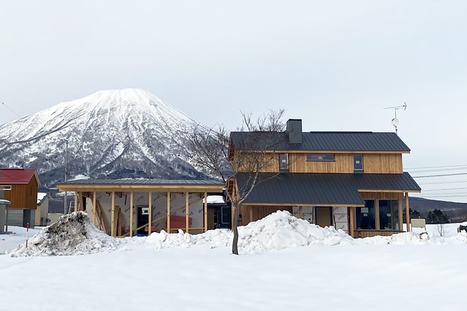 雪の羊蹄山と新築木造住宅 カラマツ無垢板張りの外壁